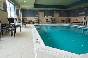 Piscina interna com espreguiçadeiras e placa de proibição de mergulho.