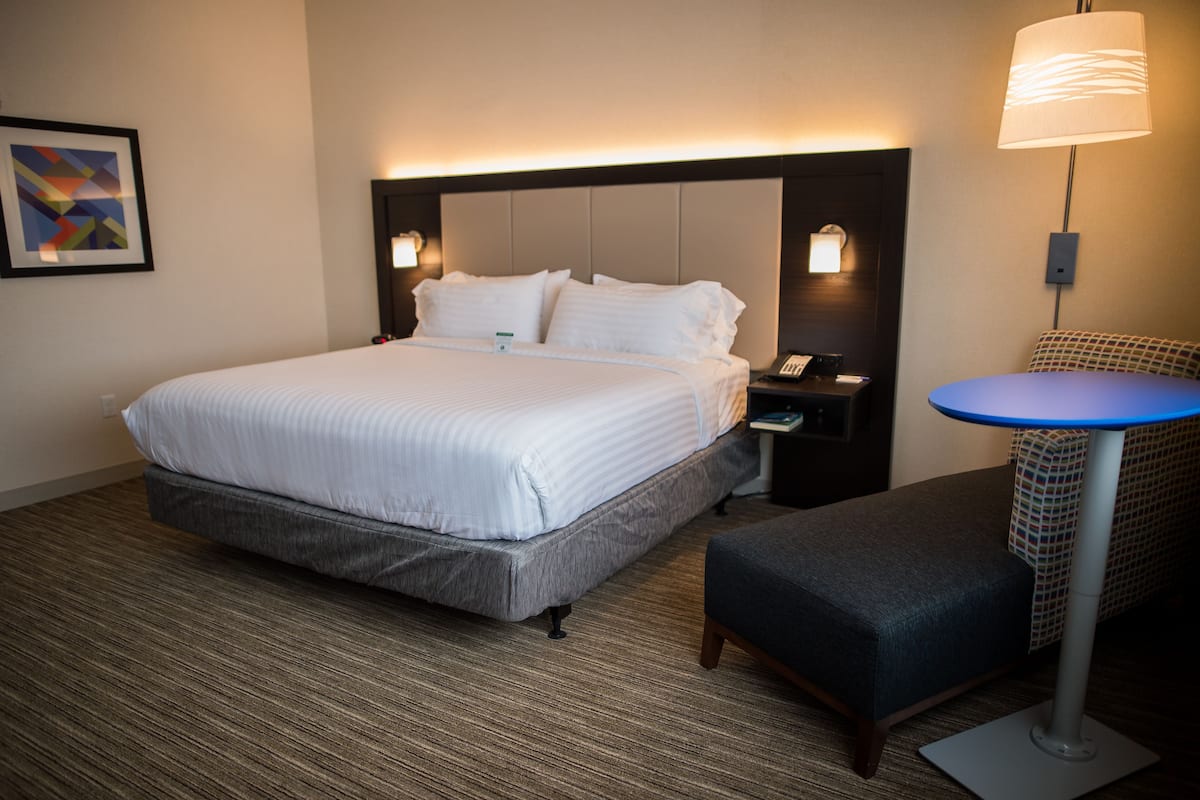 A hotel room with a large bed, bedside tables, a desk, and a chair.