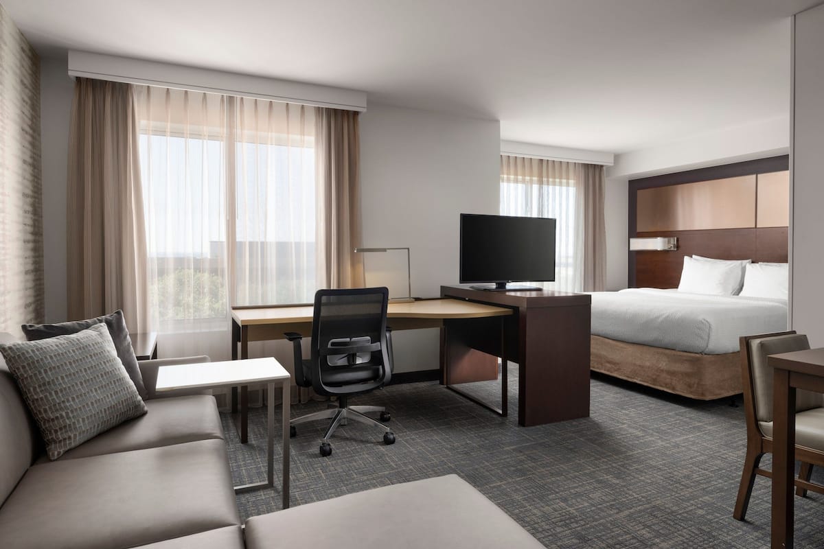A hotel room with a bed, a desk, a television, a sofa, and a chair.