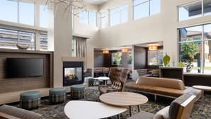 Een ruime hotel lobby met een open haard, comfortabele zithoeken en grote ramen met uitzicht op buiten.
