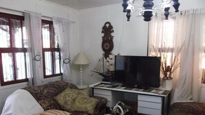 A living room with a sofa, a television, a decorative ship model, and a lamp. - Pousada Roses Canela (Canela)