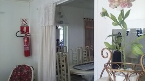 A dining area with a round table and chairs, a fire extinguisher, and a potted plant. - Pousada Roses Canela (Canela)