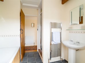 A bathroom with a bathtub, a sink, and a towel rack. - Degembris Cottages (Newquay)