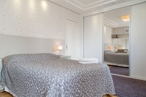 A bedroom with a bed, a nightstand, a lamp, a mirror, and a wardrobe. - Apartamento Redenção (Porto Alegre)