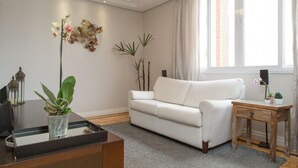 Una sala de estar moderna con un sofá blanco, una mesita de madera y una planta en maceta.