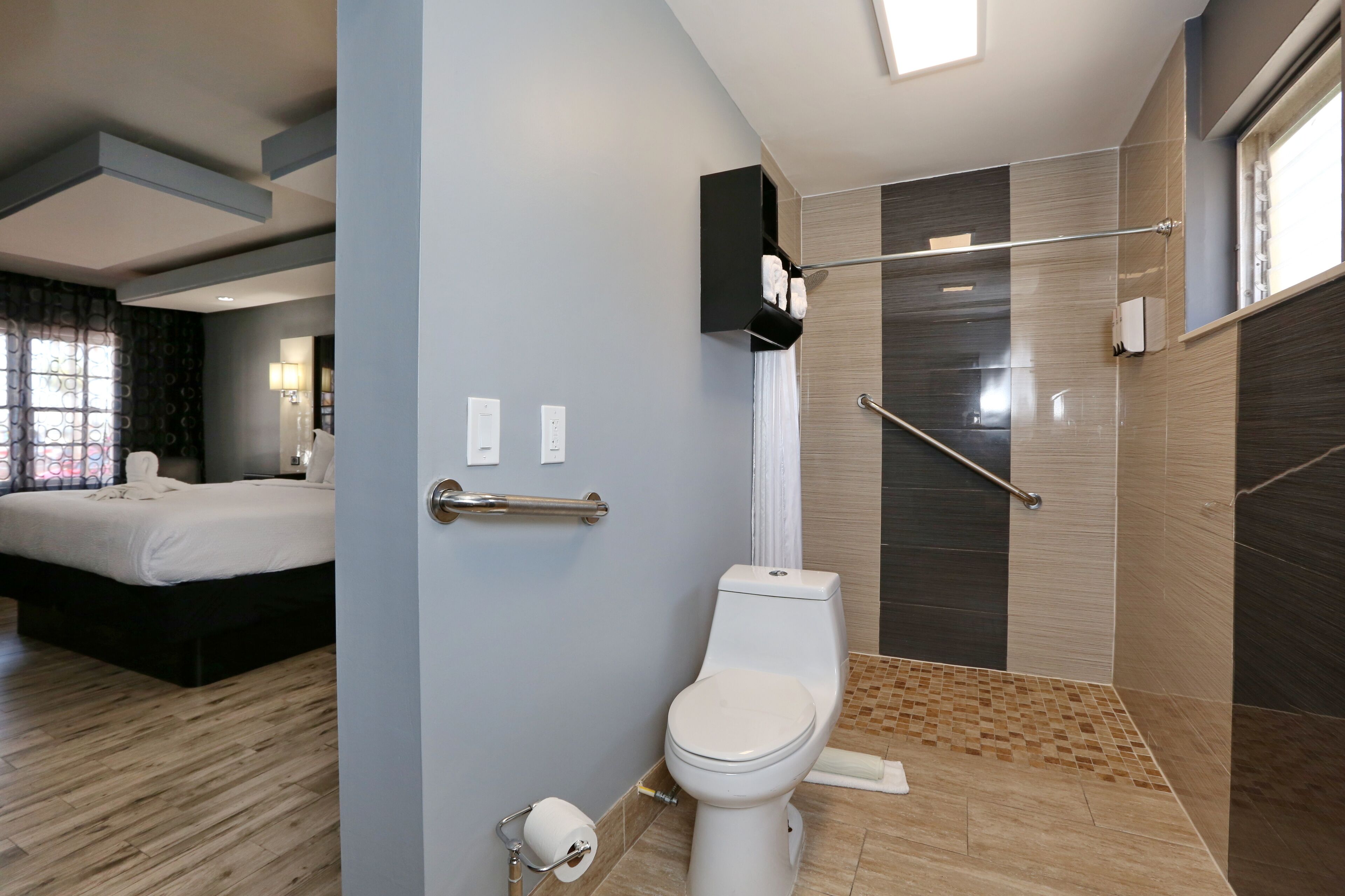 Une salle de bain moderne équipée de toilettes, d’une douche et d’un espace douche séparé par des parois en verre.