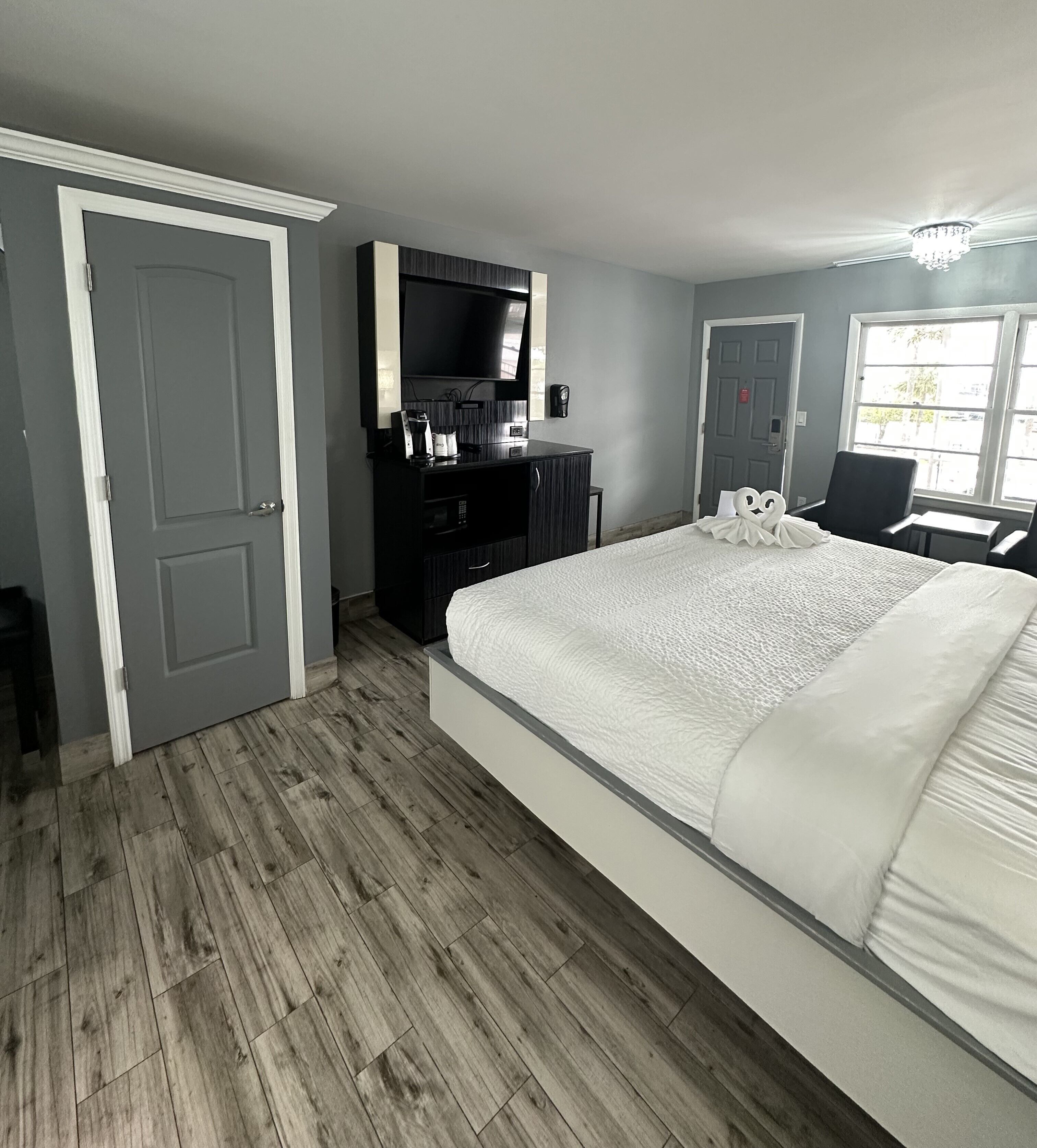 A hotel room with a large bed, a TV mounted on the wall, a coffee maker, and a desk with a chair.