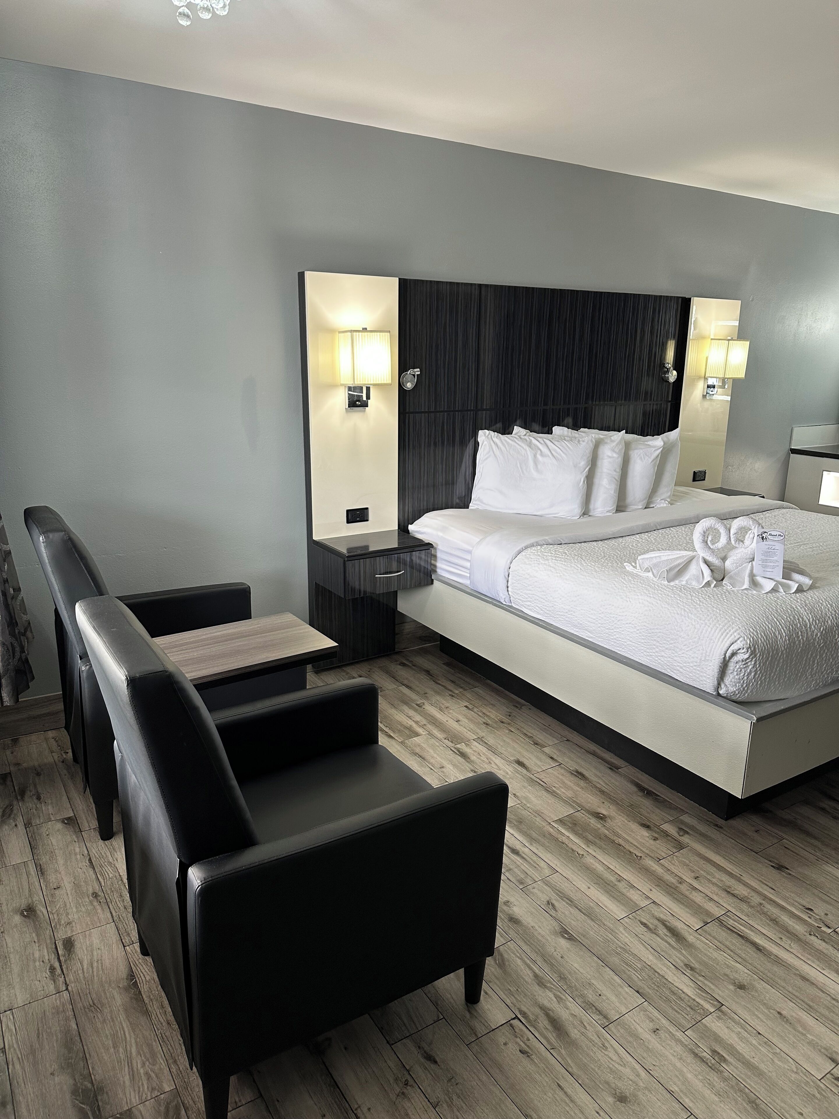 A modern hotel room with a large bed, a desk, and a seating area.