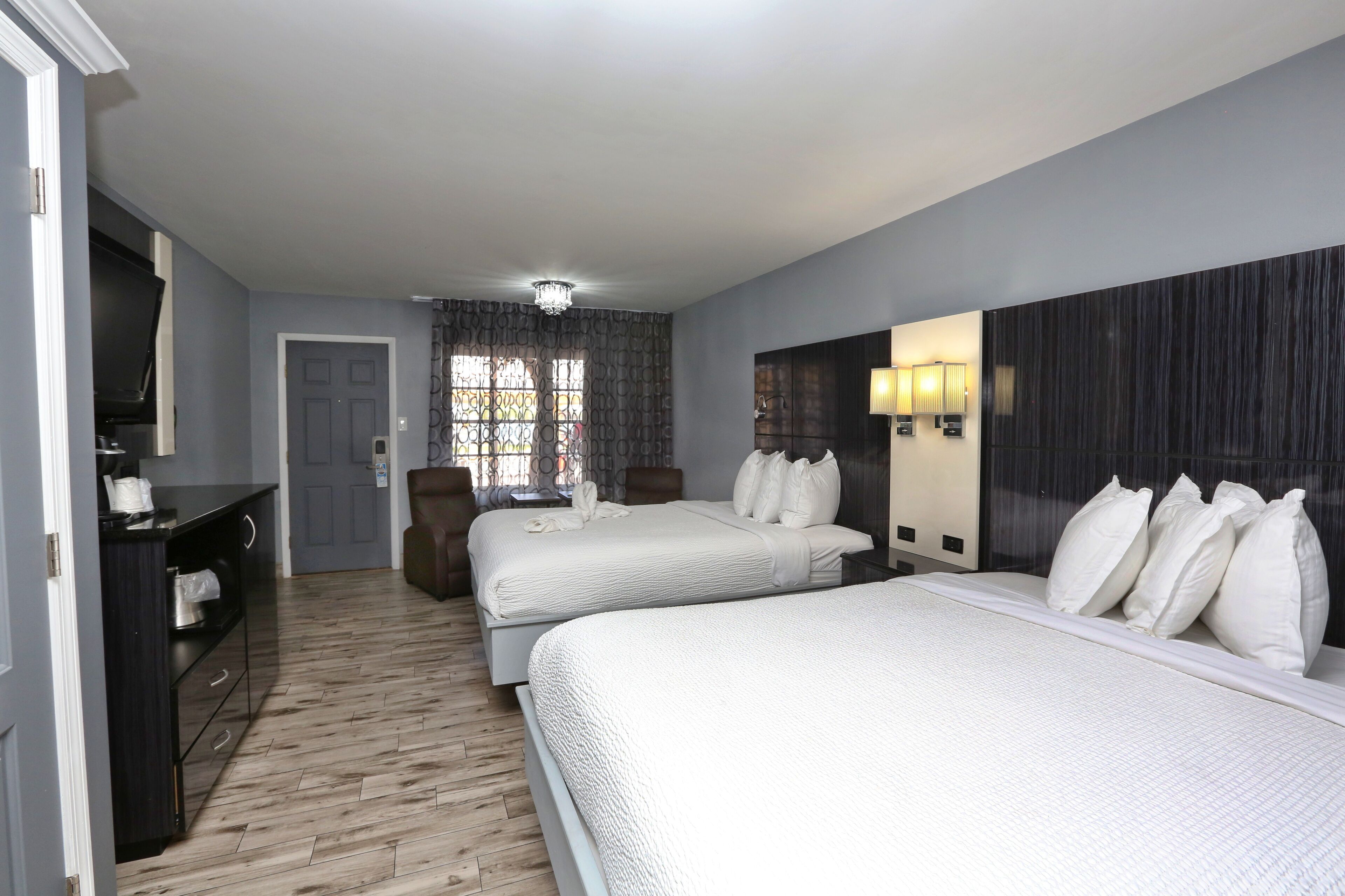 A hotel room with two beds, a desk, and a TV.