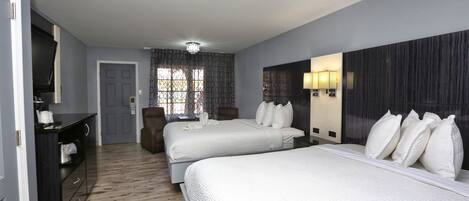 A hotel room with two beds, a desk, and a TV.