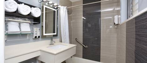 A modern bathroom with a bathtub, a sink, a mirror, and a shower area.