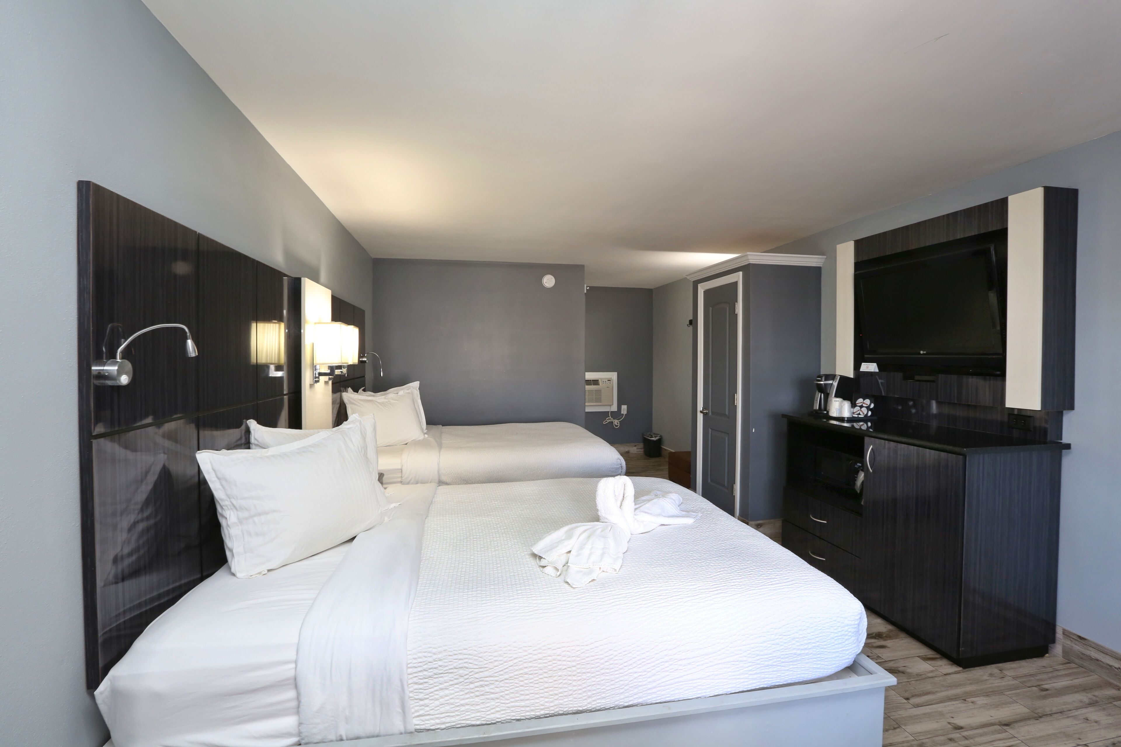 A hotel room with two beds, a TV, a minibar, and a desk.