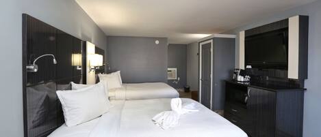A hotel room with two beds, a TV, a minibar, and a desk.