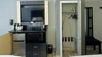 Quarto de hotel com duas camas, cozinha compacta equipada com micro-ondas, mini-frigorífico, televisão e banheiro com ferro e tábua de passar.
