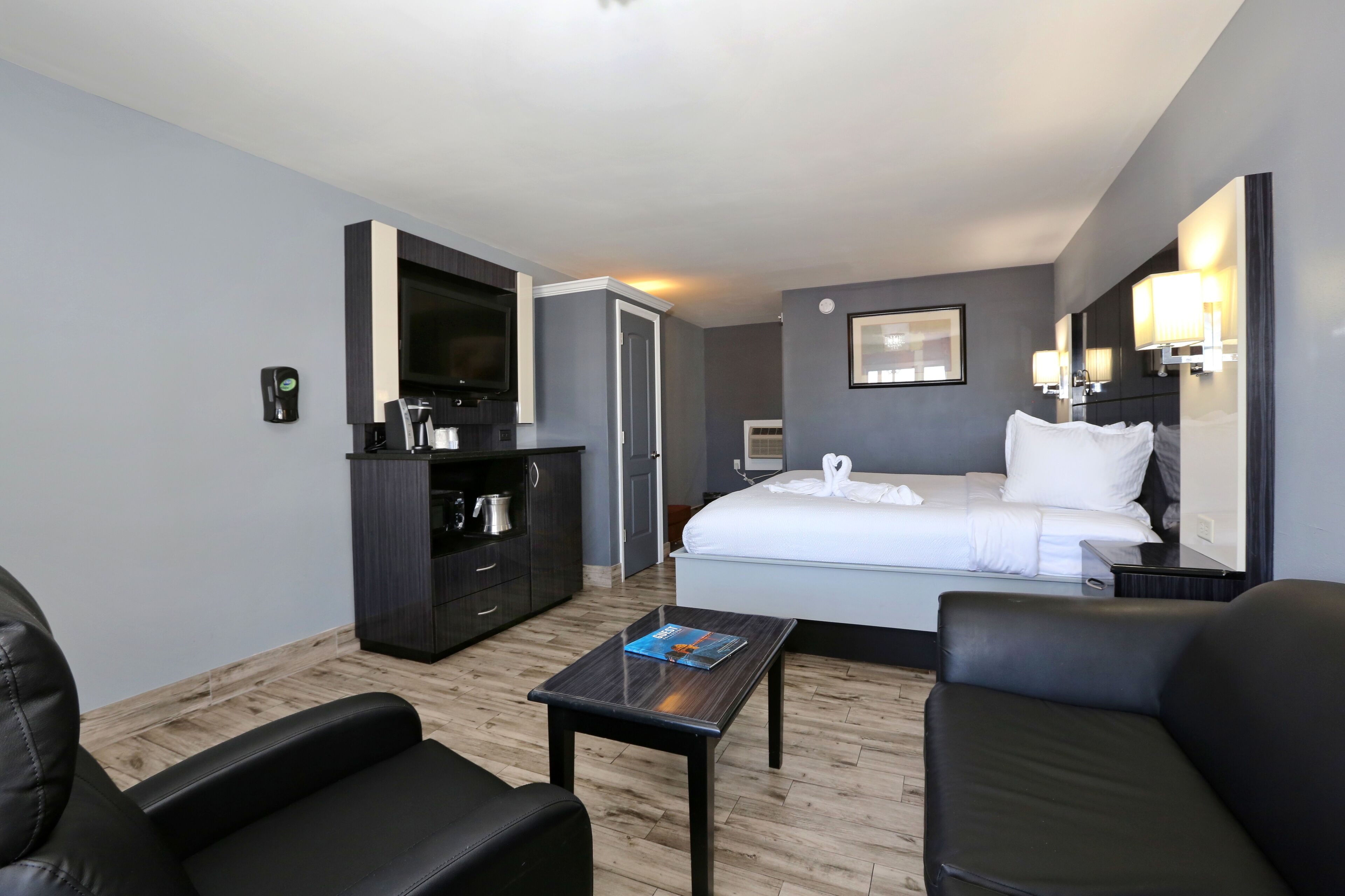 Une chambre d’hôtel équipée d’un lit, d’un bureau, d’une chaise, d’une télévision, d’un minibar et d’une salle de bain.