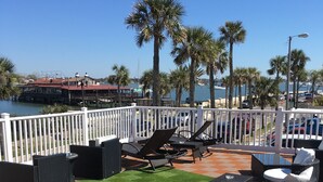 A deck with outdoor furniture, a view of the water, and a distant building. - Marion Motor Lodge (St. Augustine)