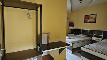 A compact room with a bed, a desk, a chair, and a small refrigerator.