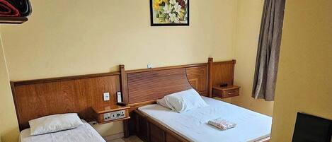 Una habitación de hotel con dos camas individuales, un cabecero de madera, un escritorio pequeño y una mesita de noche.