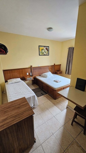 Una habitación de hotel con dos camas individuales, un cabecero de madera, un escritorio pequeño y una mesita de noche.