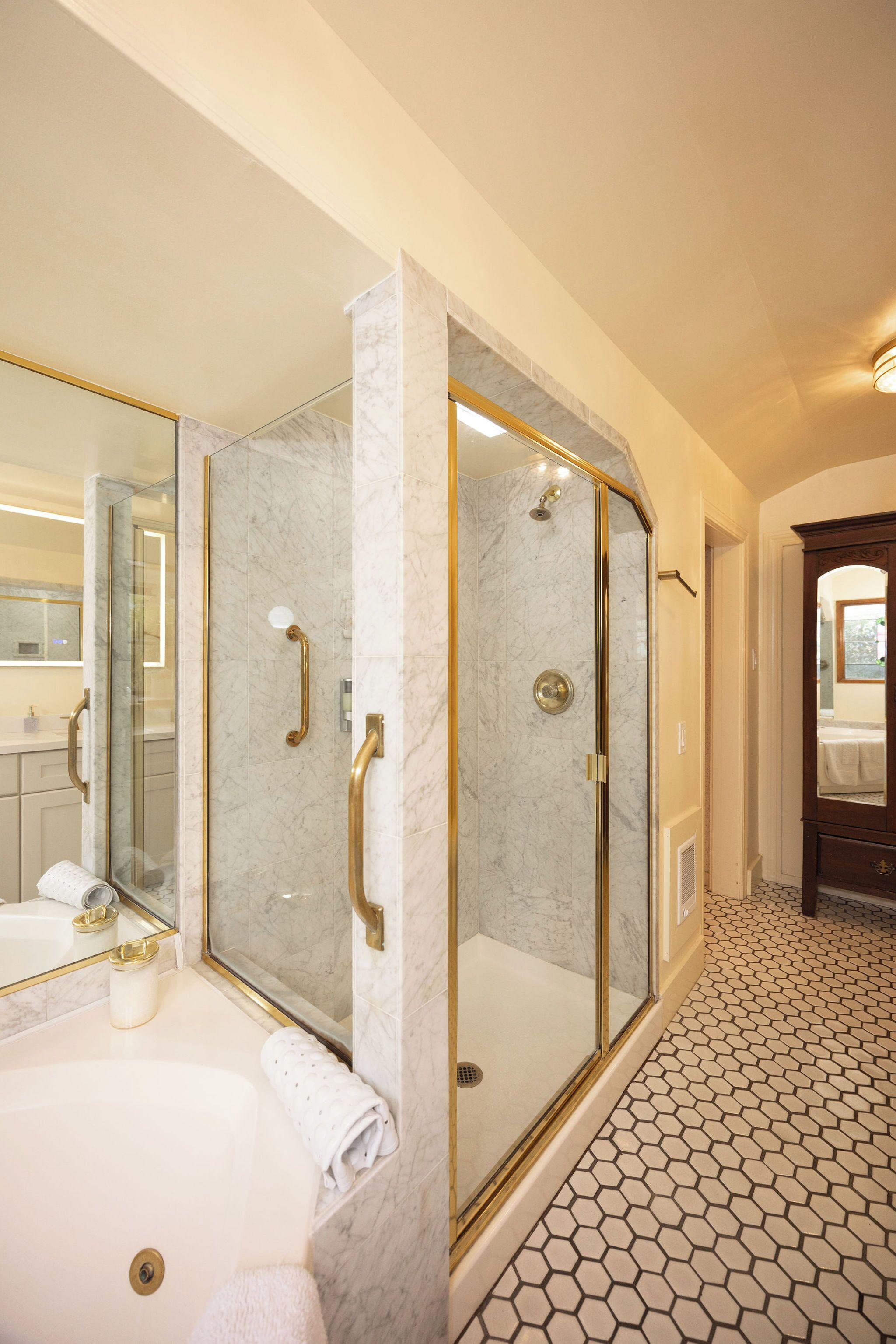 A modern bathroom with a glass-enclosed shower, a bathtub, and a vanity with a mirror.