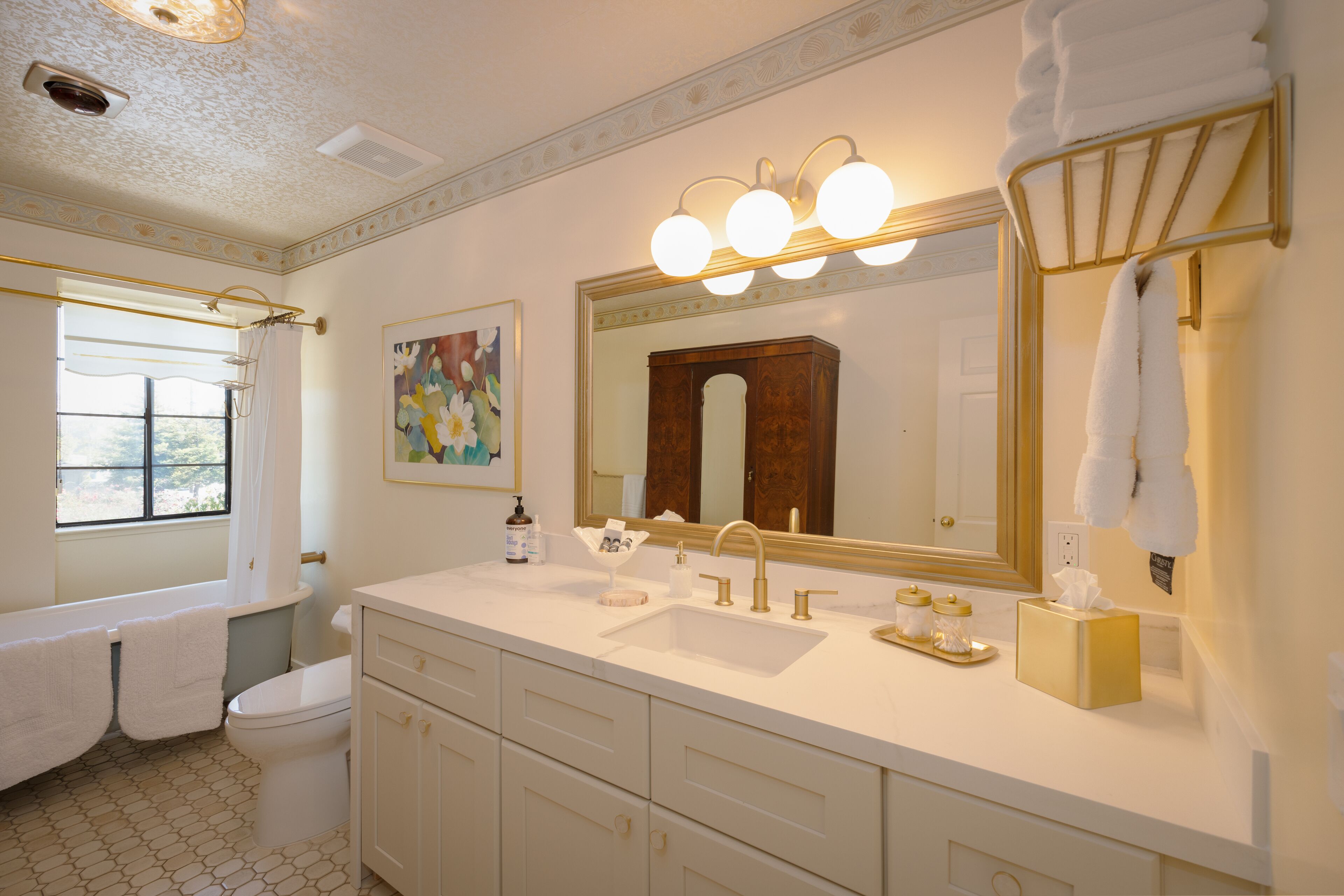 A bathroom with a double sink, vanity, and a large mirror with lights.