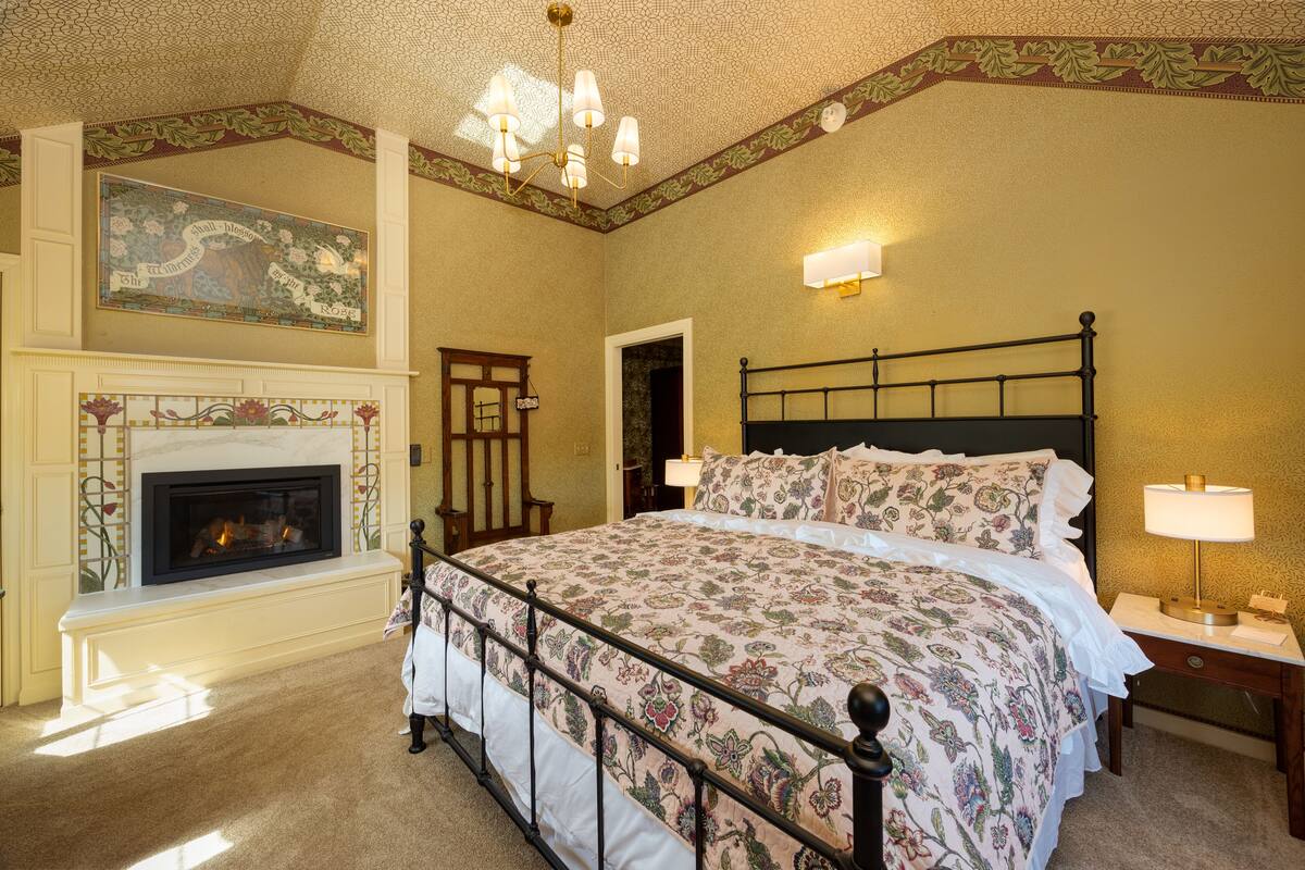 Una camera da letto con un letto grande, un camino e un lampadario.