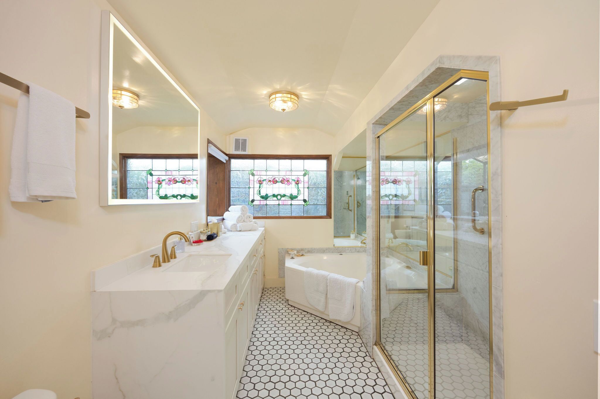 Une salle de bain avec deux lavabos, une baignoire, une douche à parois de verre et un grand miroir.