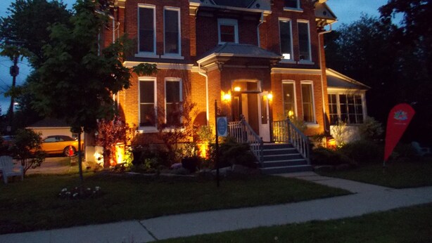 A two-story brick house with a front porch, steps, and a driveway.