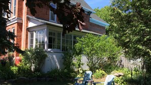 A backyard with a brick house, a covered patio, and a wooden fence.