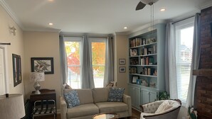 A cozy living room with a beige sofa, a round coffee table, a bookshelf, and a fireplace.