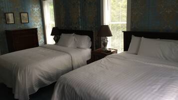 Ett hotellrum med två sängar, ett nattduksbord med en lampa och ett fönster med persienner.