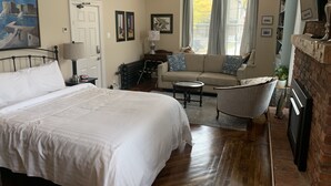A bedroom with a large bed, a sofa, a coffee table, and a fireplace.