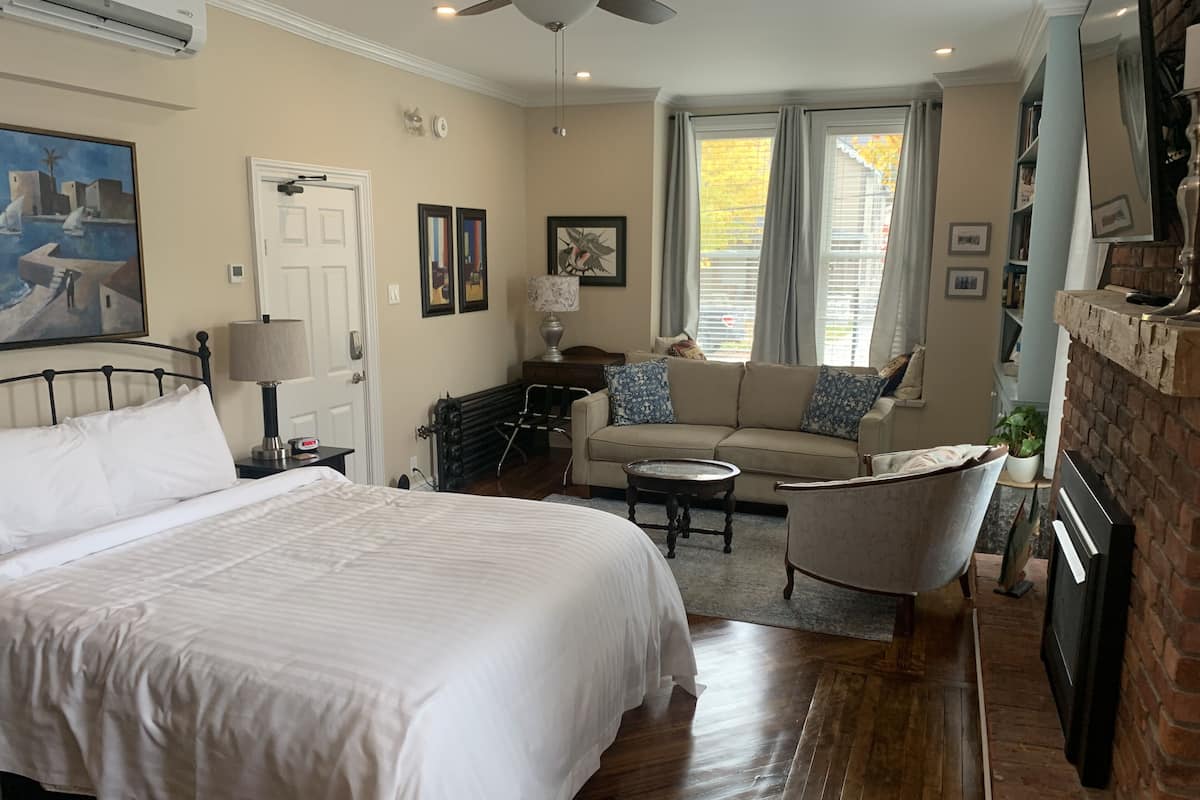 A bedroom with a large bed, a sofa, a coffee table, and a fireplace.