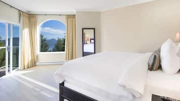 Quarto com cama grande, varanda com cortinas e vista para montanhas.