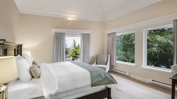 A bedroom with a bed, a chair, and large windows.