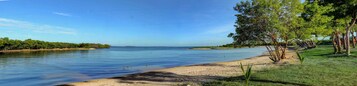 Um lago calmo com uma praia arenosa e árvores ao longo da margem.