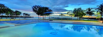 Piscina com vista para o pôr do sol e palmeiras.