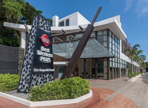 El exterior del Hotel Byllwall, con un llamativo letrero de 'BW Best Western PLUS', arquitectura moderna y un área de entrada ajardinada.