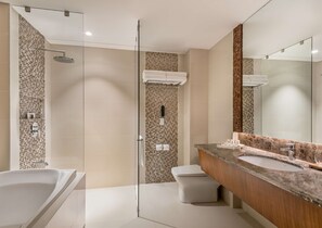 Un baño moderno con ducha de vidrio, una bañera independiente y un lavamanos con un espejo grande.