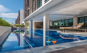 Un espace piscine moderne, avec une vue dégagée sur la piscine, des chaises longues et un bar.
