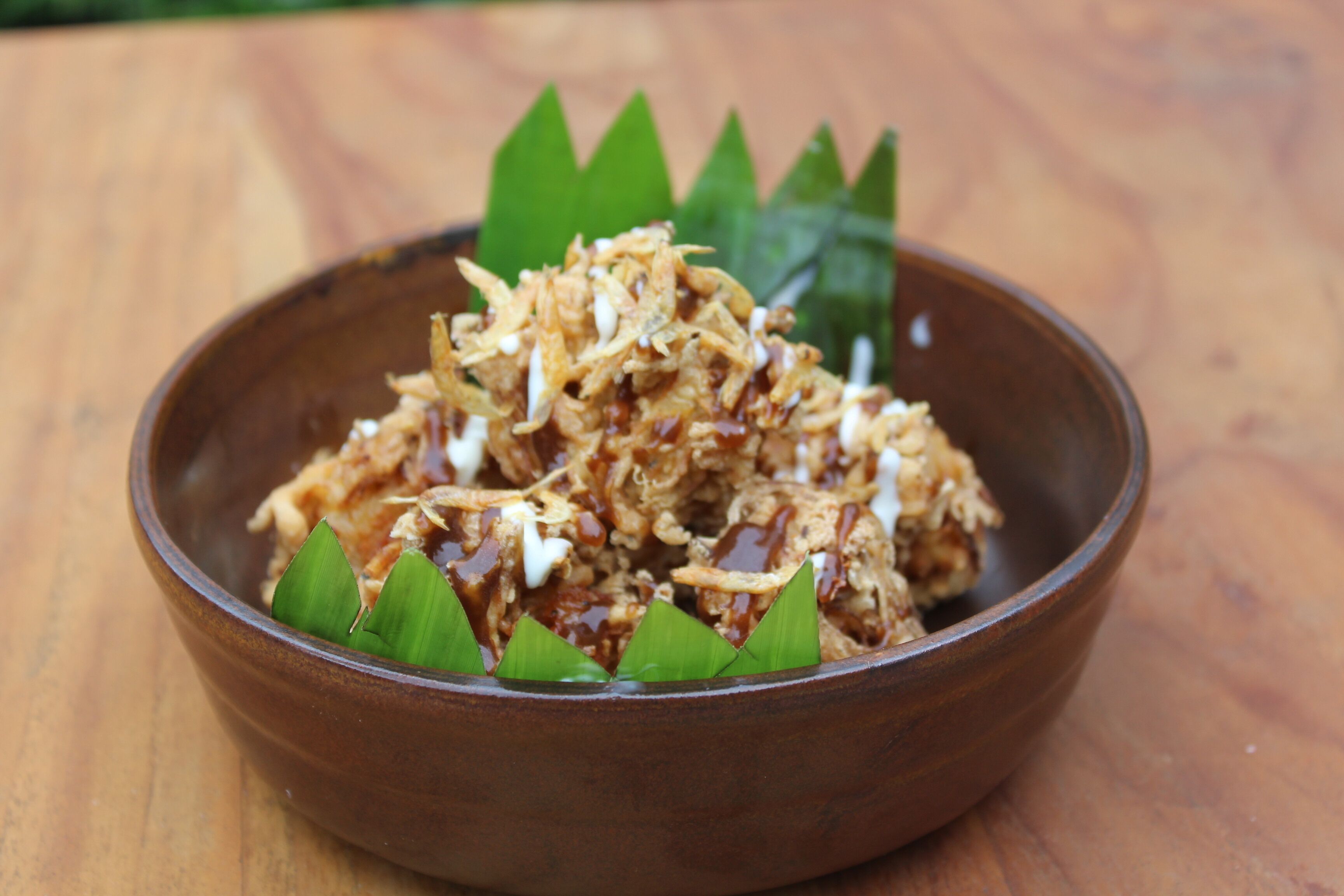A bowl of food with shredded ingredients and a green leaf garnish.