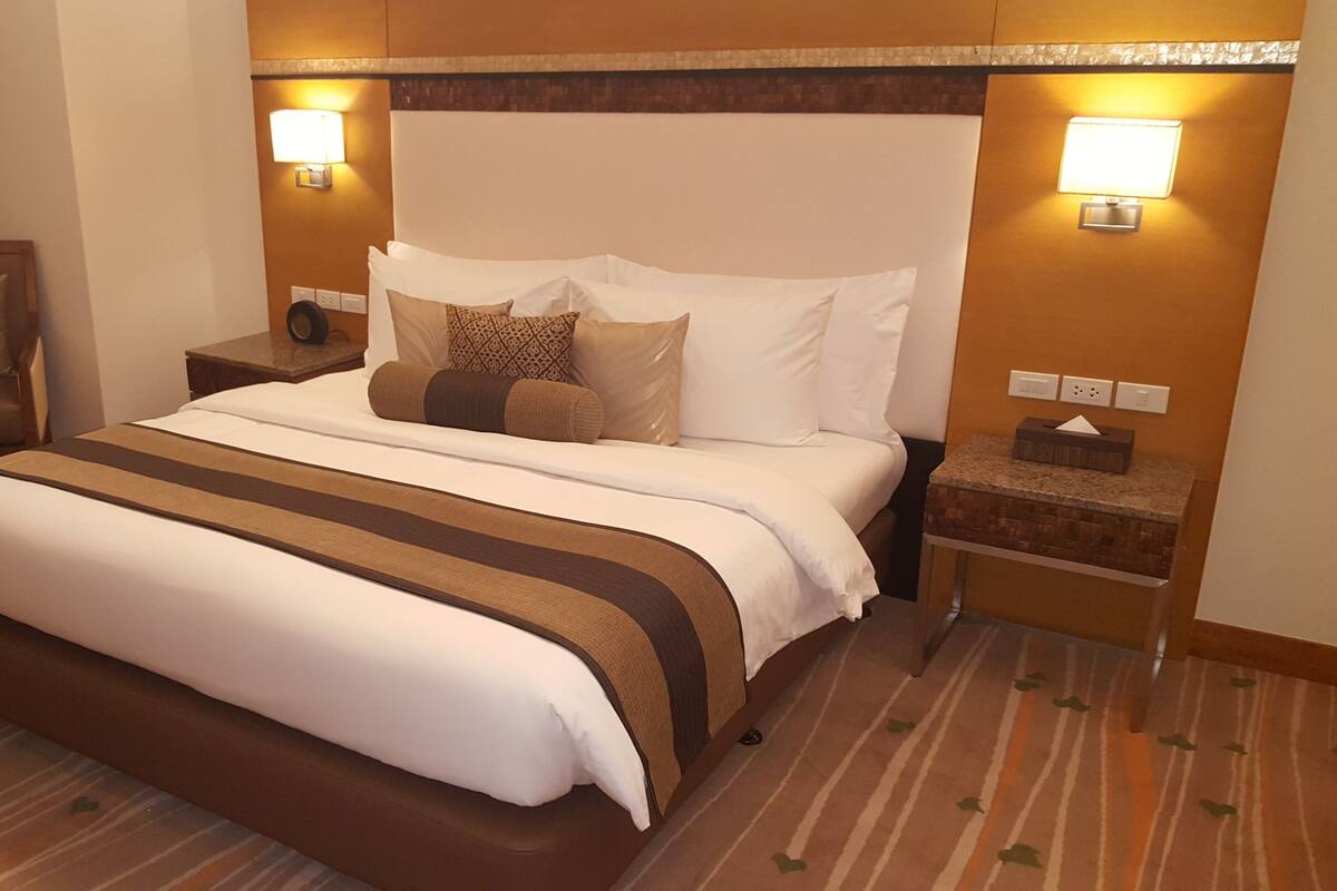 Ein Hotelzimmer mit einem großen Bett, einem Sessel, zwei Nachttischen und Wandleuchten.