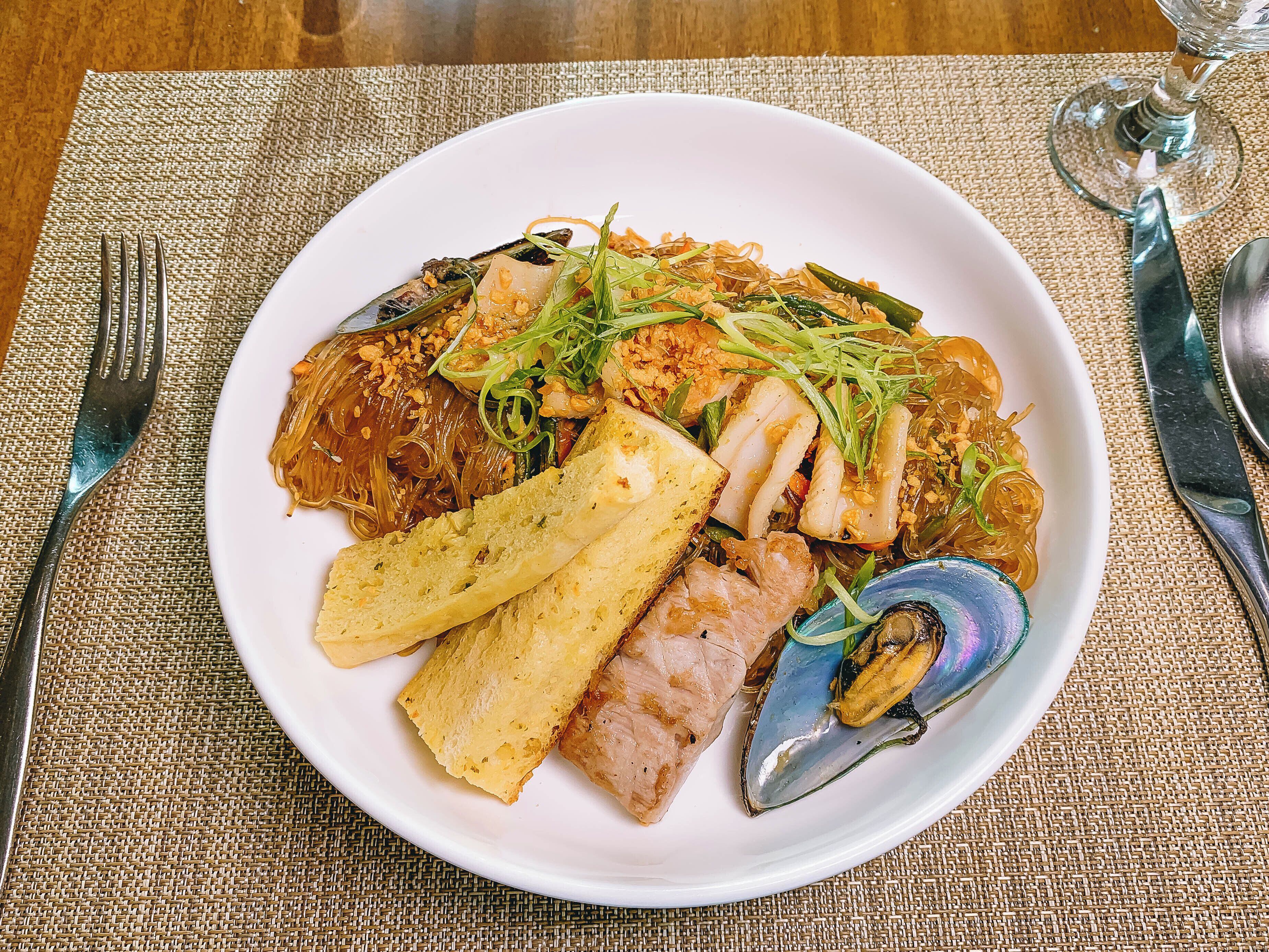 A plate of food with various seafood and vegetables on a white plate.