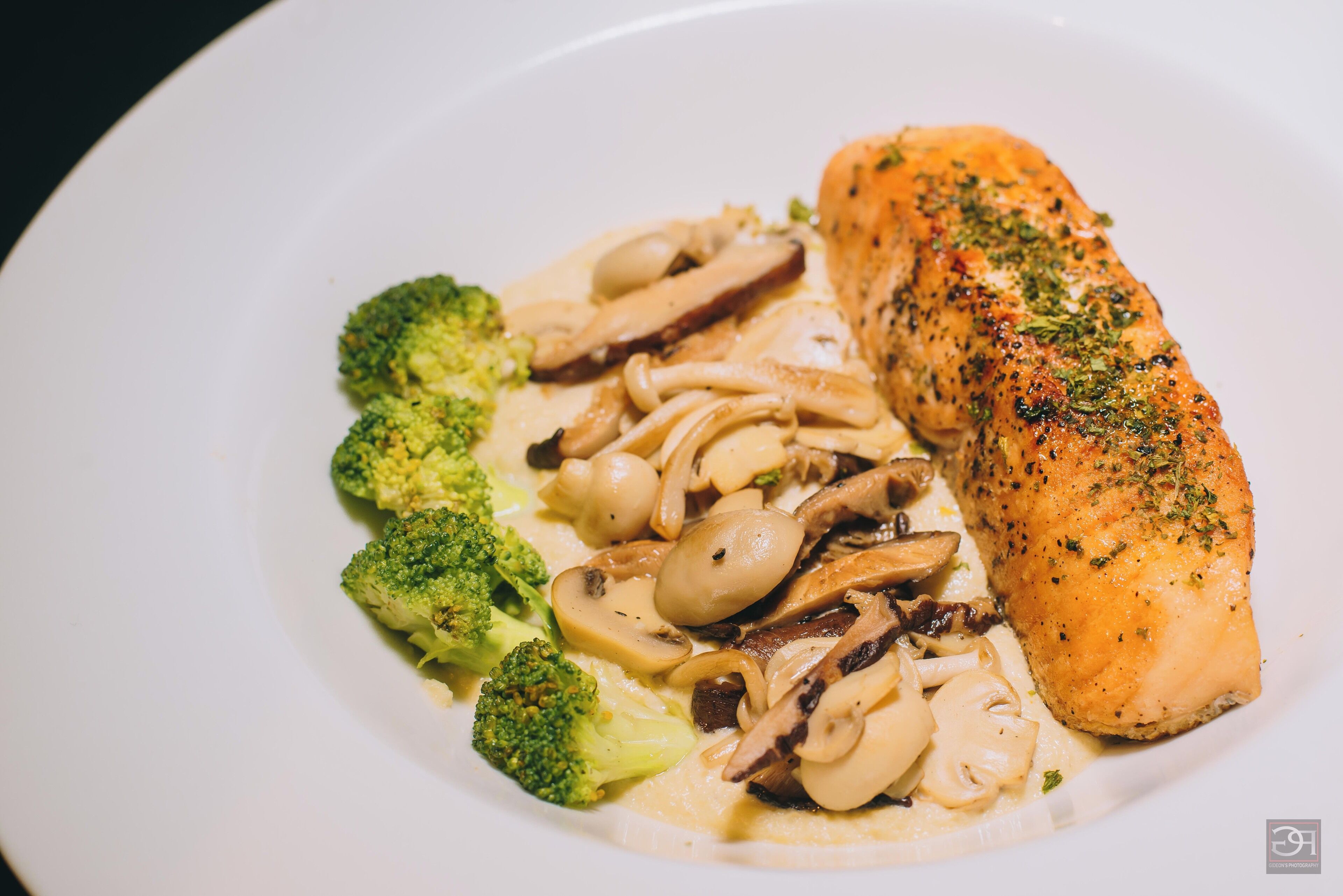 A plate with salmon, broccoli, and mushrooms.