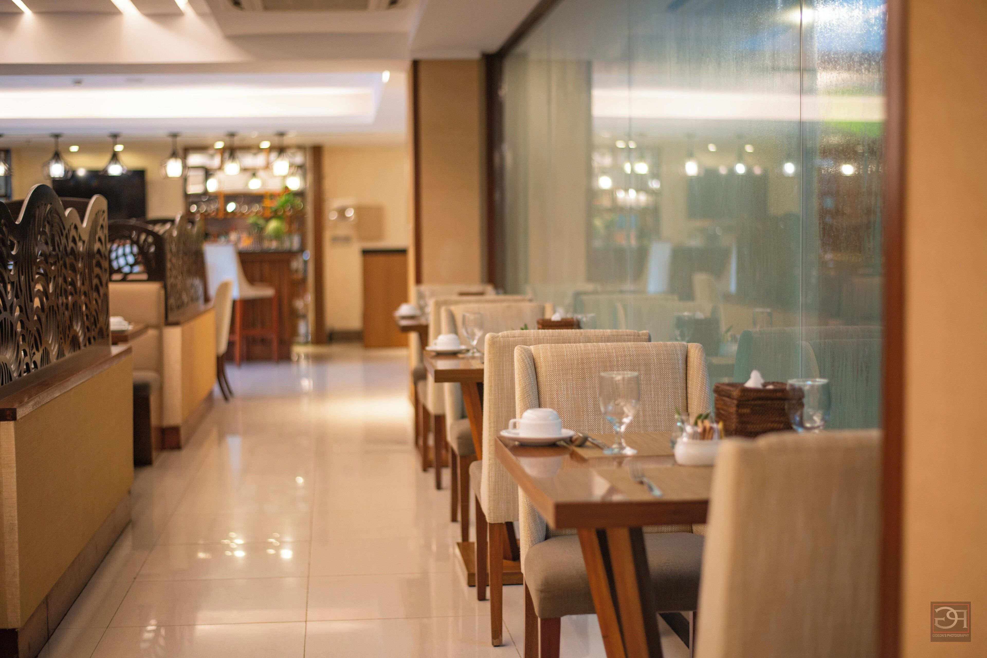 Un restaurante con una barra larga, varias mesas y sillas.