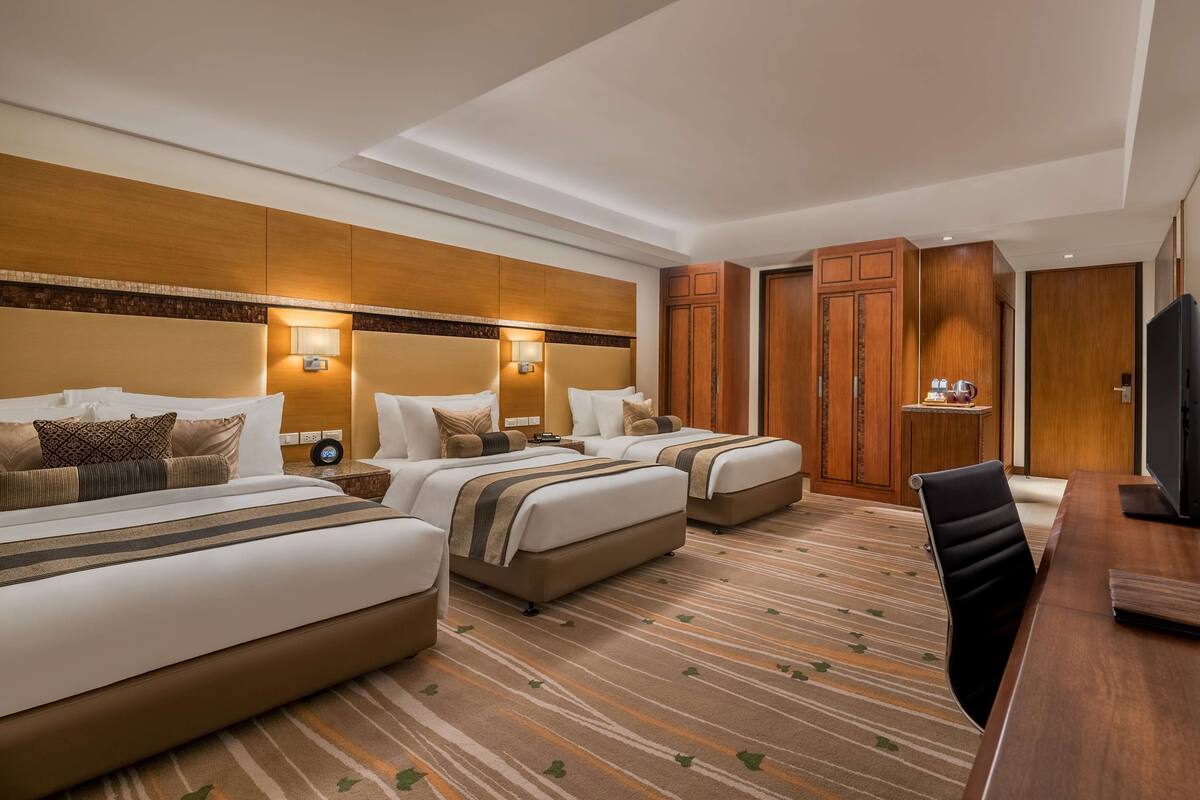 Ein Hotelzimmer mit zwei Betten, einem Schreibtisch, einem Fernseher und einem Kleiderschrank.