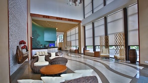 A spacious lobby with a curved floor, seating areas, and large windows.