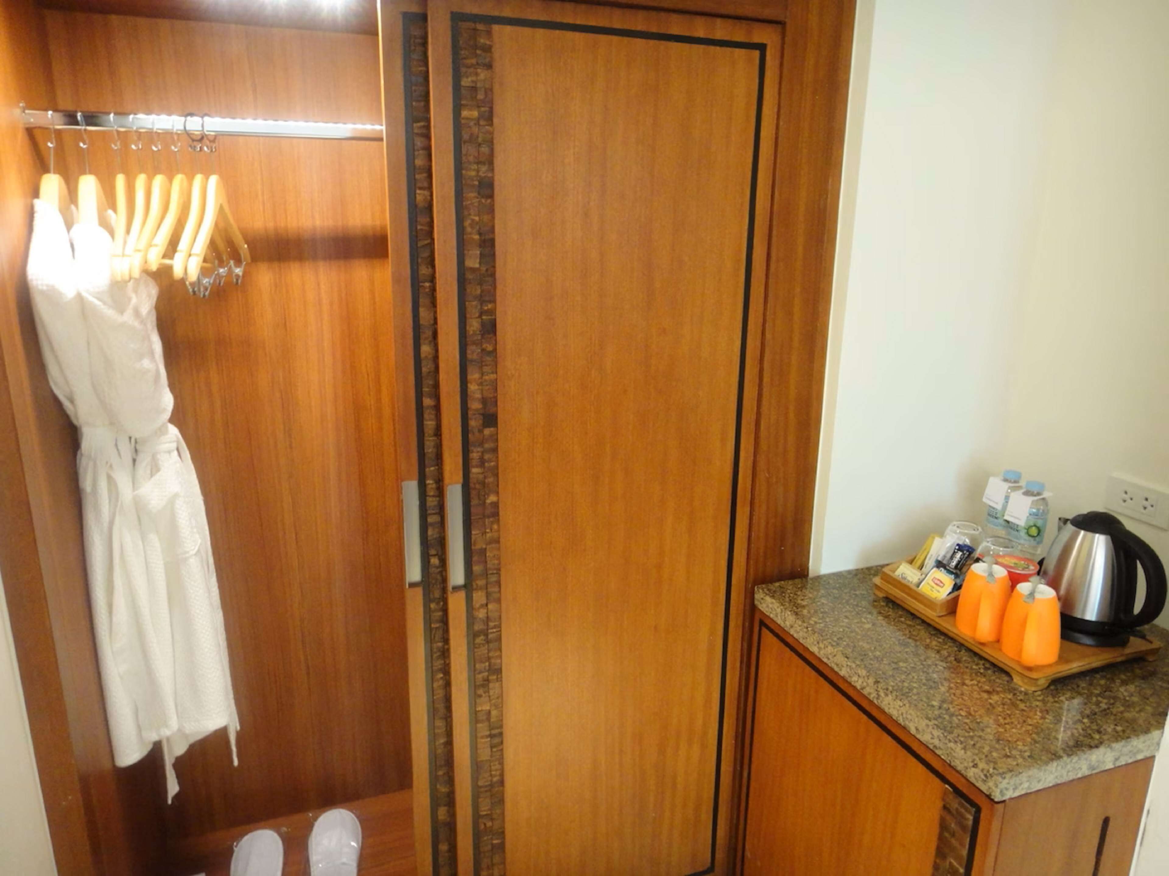 A hotel bathroom with a wooden vanity, a robe hanging on a rack, and toiletries on the counter.