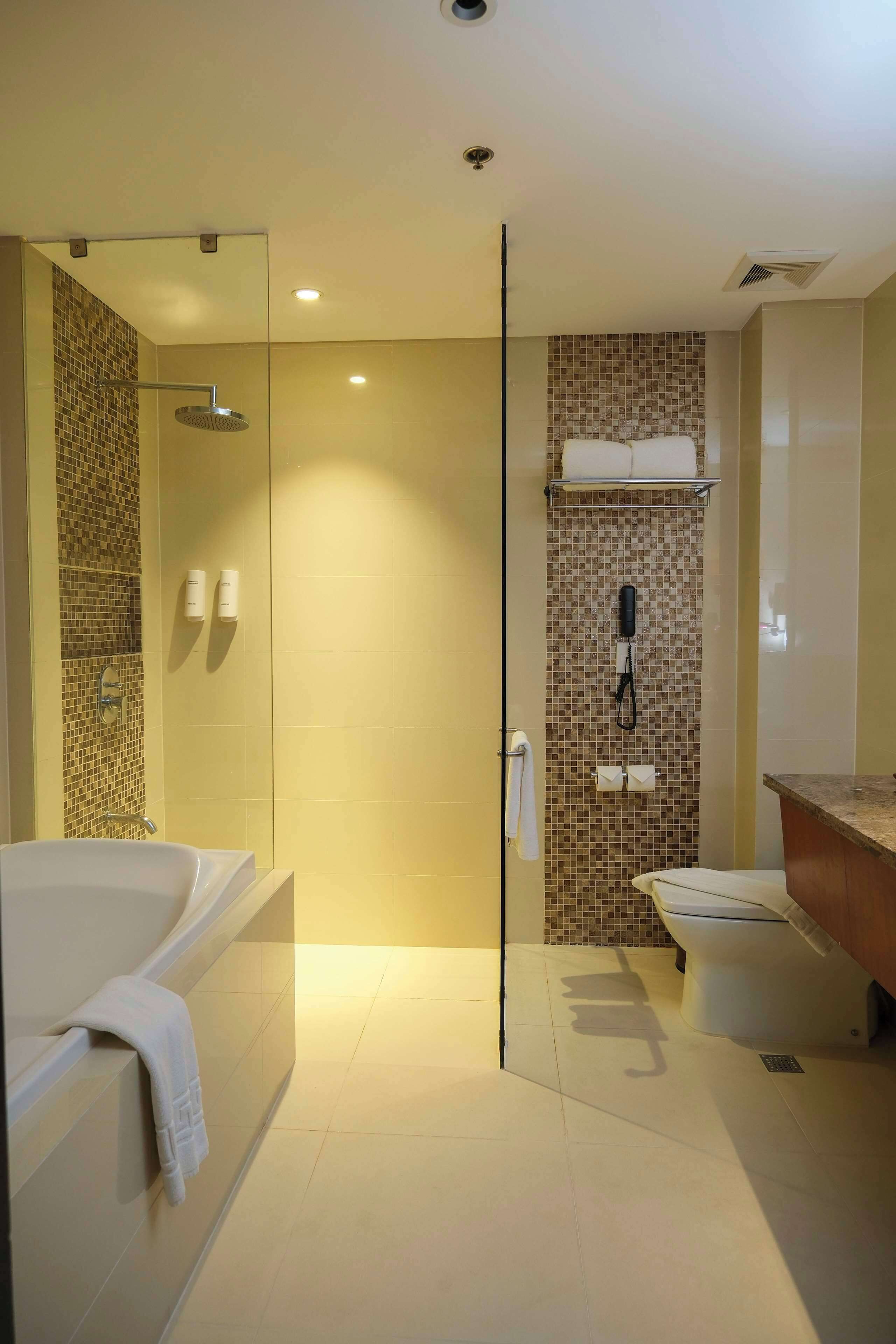 A modern bathroom with a glass-enclosed shower, a standalone bathtub, and a toilet.