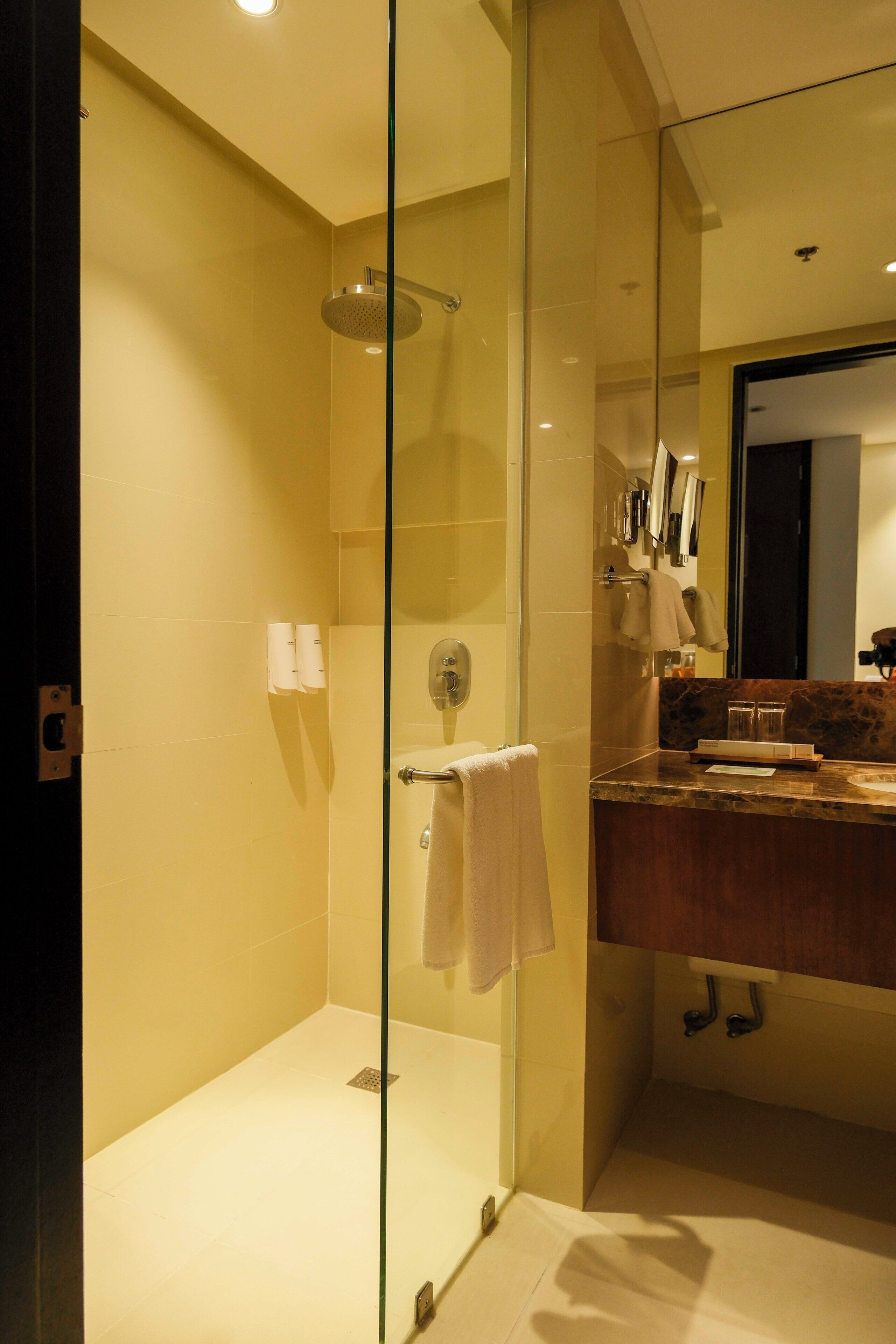 A modern bathroom with a glass-enclosed shower, a wooden vanity, and a large mirror.